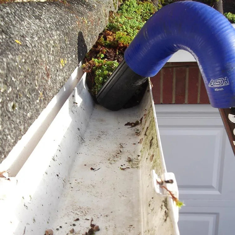 Clearing a moss-filled gutter with a gutter vacuum